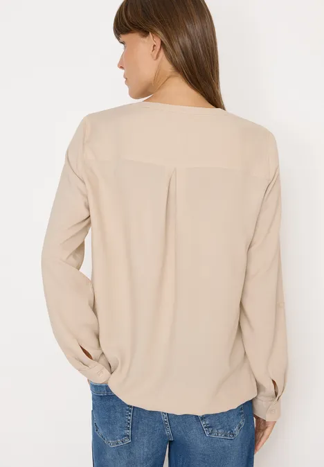 Frau mit beiger Bluse und blauer Jeans von hinten fotografiert.